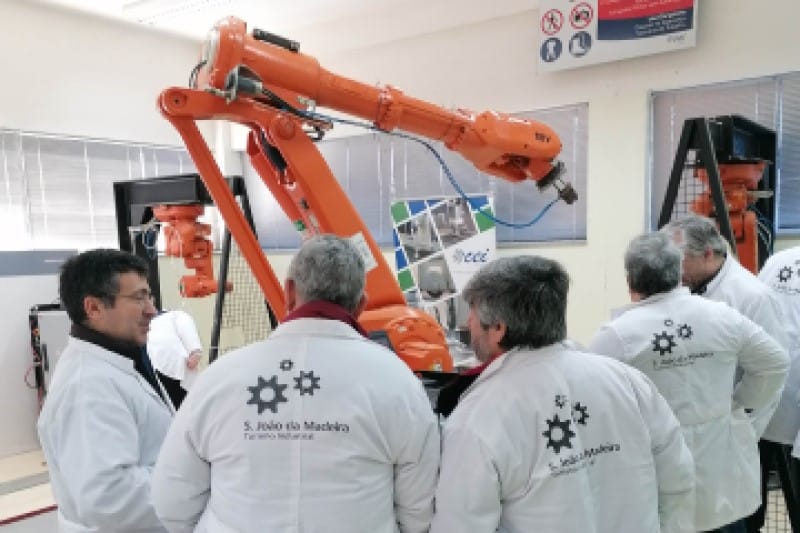 Um conjunto de pessoas com batas brancas que se encontram a observar um equipamento de laboratório.